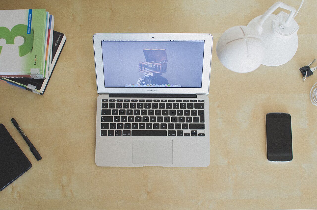 A laptop, phone and notebooks on a desk